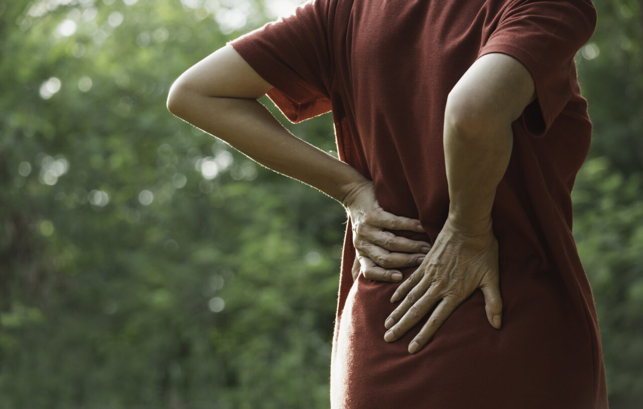 Closeup hands of woman touching her back pain in healthy concept on nature background.